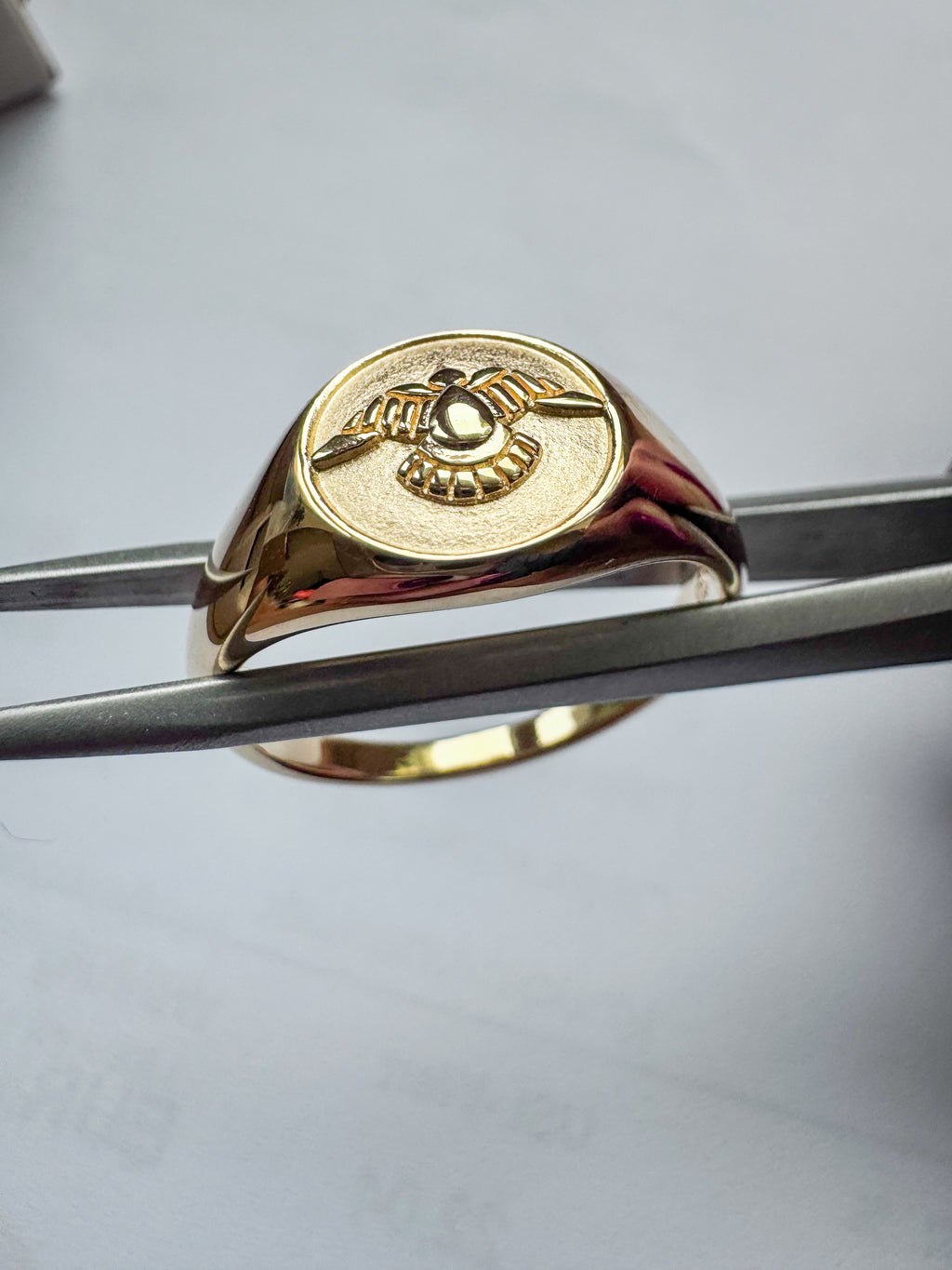 gold-plated sterling silver signet ring with a raised winged emblem on an oval face