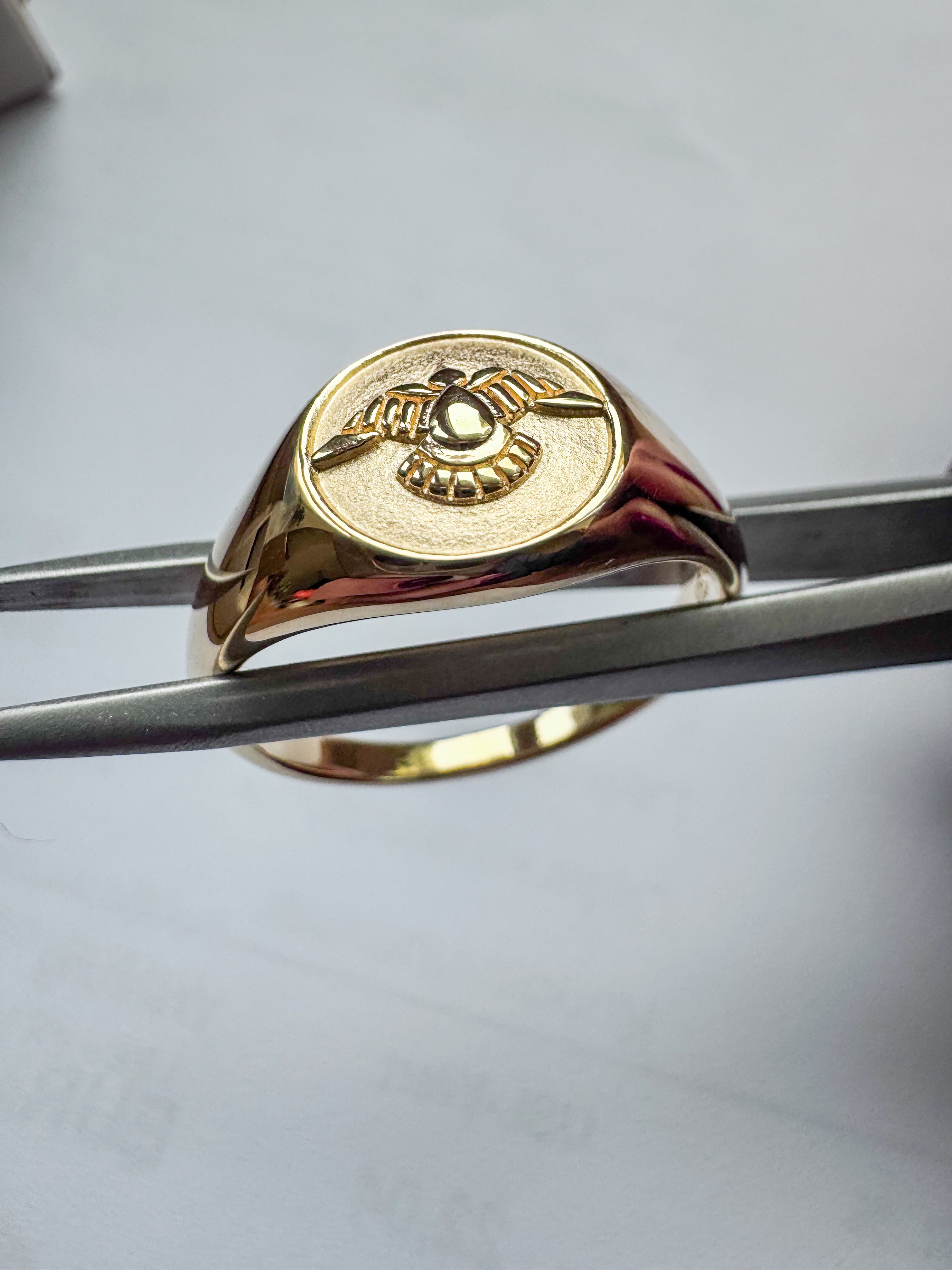gold-plated sterling silver signet ring with a raised winged emblem on an oval face