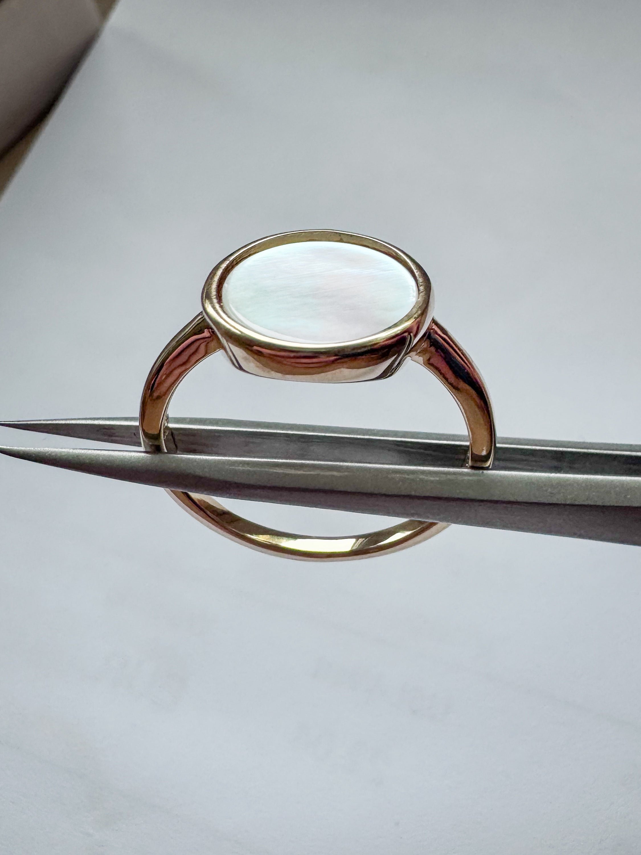 Gold-plated sterling silver ring with a round white mother of pearl stone on a slim band, bezel setting